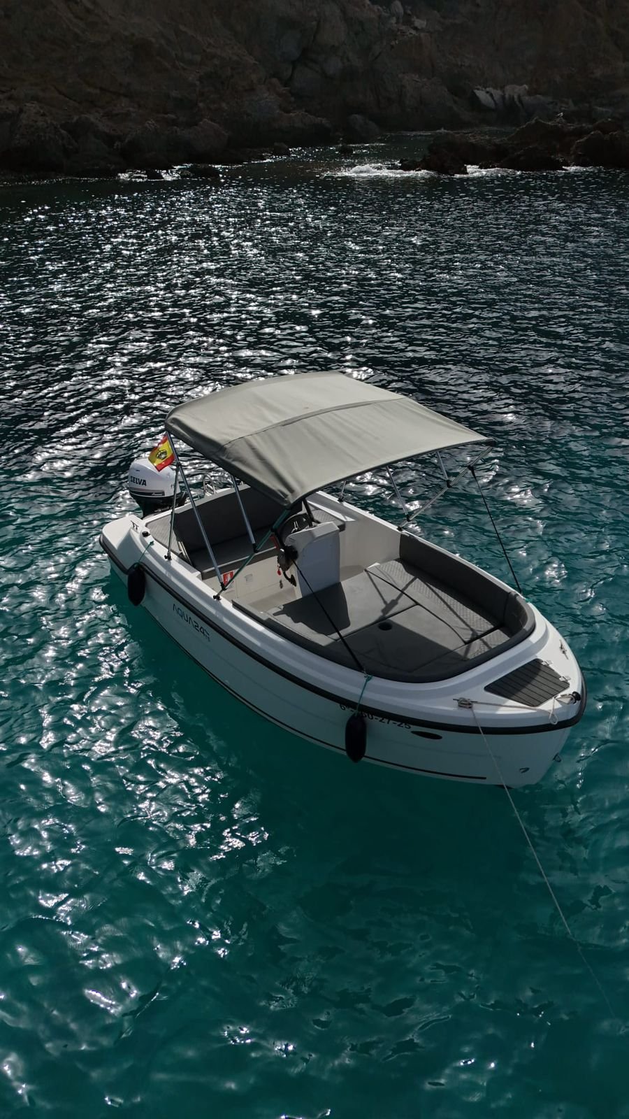 Aqua 24 licence-free boat moored in a secluded Mallorca cove with dramatic cliffs