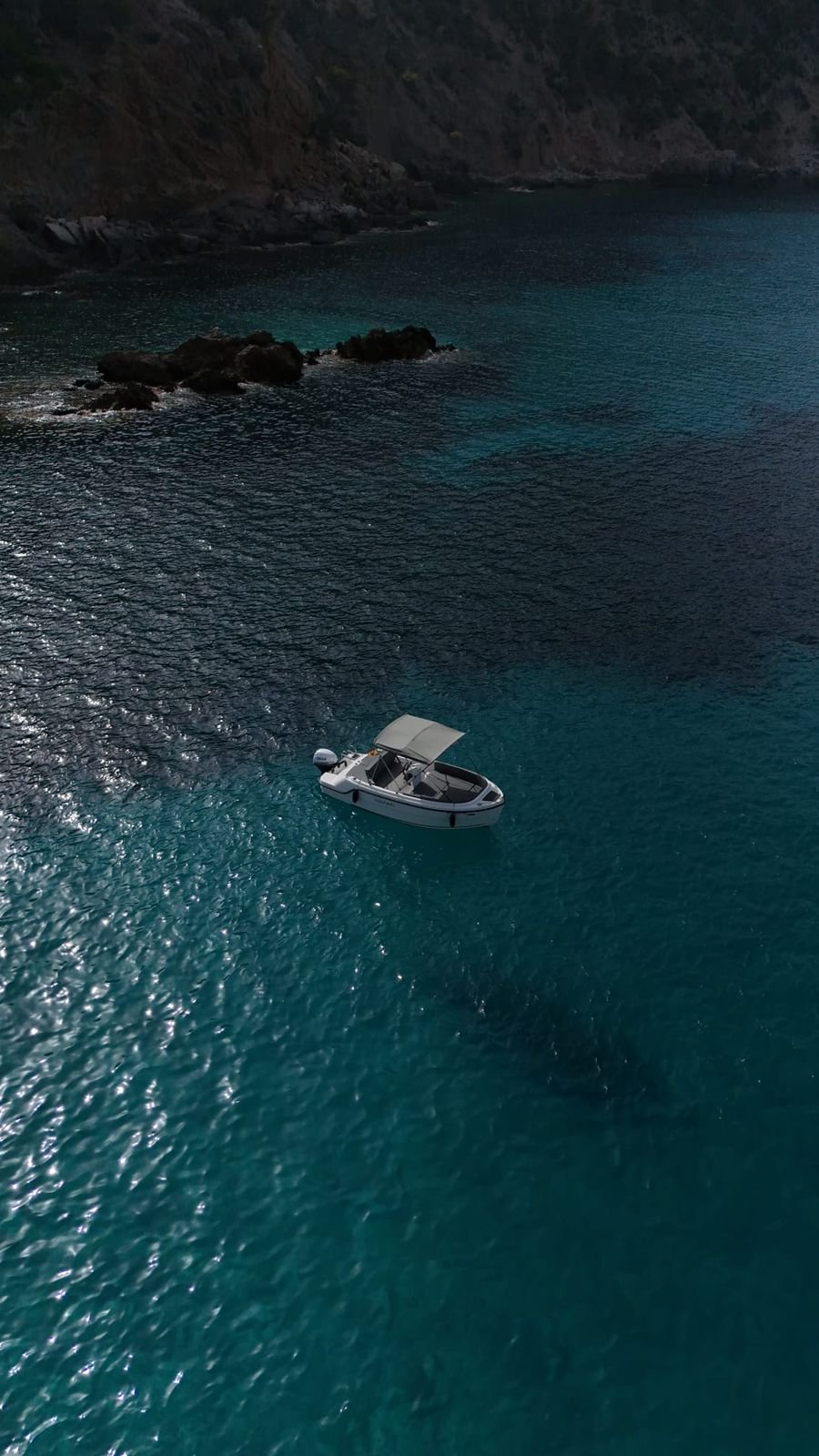White boat reflected on silvery Mediterranean water along Mallorca's coastline